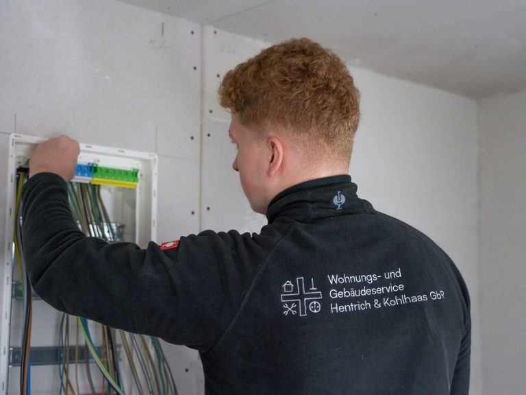 Techniker installiert Kabel in einem Schaltkasten an einer Wand.