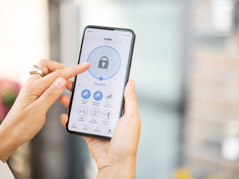 Händed mit Smartphone, das ein Sicherheitssymbol und Steuerelemente anzeigt.