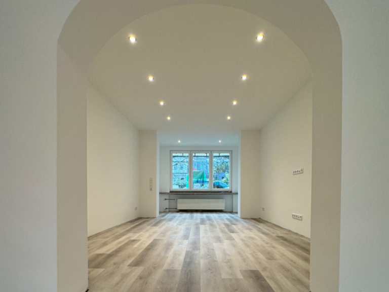 Innenraum eines Hauses mit sichtbaren elektrischen Leitungen und Möbeln.