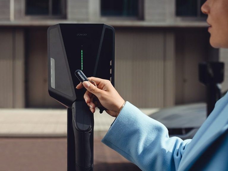 Ladestation für Elektroautos mit Anzeige und Kabelhalterung an einer Wand.