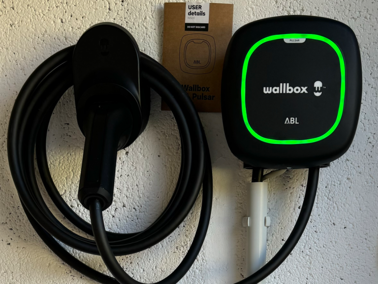 Ladestation für Elektroautos mit Anzeige und Kabelhalterung an einer Wand.