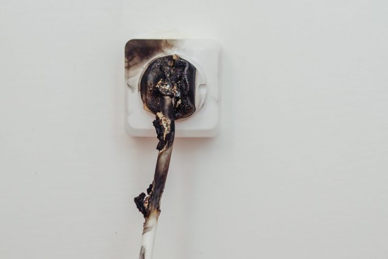 Verbrannter Stecker in einer Steckdose mit beschädigten Kabeln.